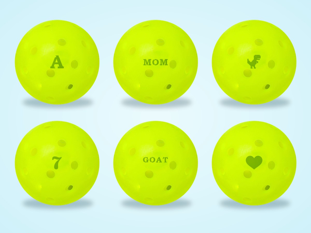 Six pickleballs stamped A, MOM, a dinosaur, 7, GOAT and a heart