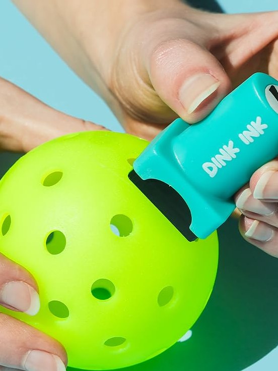 Pressing the Dink Ink stamper onto a pickleball